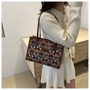 Dettaglio della borsa tote a scacchi con finiture in pelle marrone e motivo jacquard