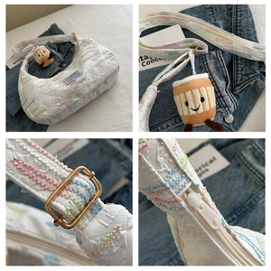 Detail of white half-moon bag featuring colorful floral embroidery and fashion tag