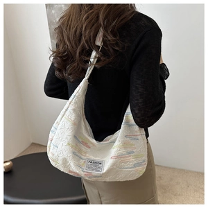 Dettaglio della borsa a mezzaluna in tela ricamata con trama tessuta e etichetta fashion