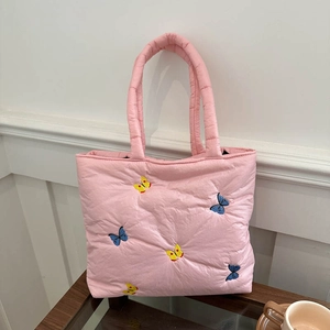 Pink quilted tote bag featuring multi-color butterfly embroidery on a wooden table