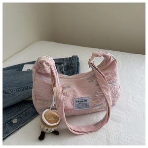 Detail of pink quilted shoulder bag with wave embroidery and plush coffee cup charm