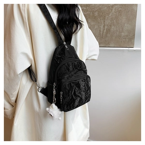 Detail of black pleated nylon crossbody bag with multi-pocket and plush charm on the side