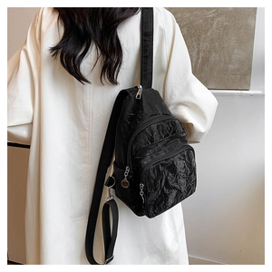 Detail of black pleated nylon crossbody bag showing multiple zipper pockets and wide strap