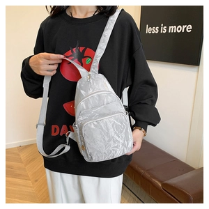 Detail of silver metallic textured crossbody bag showing zipper compartments and strap