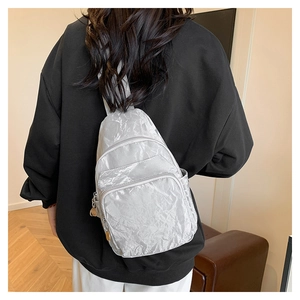 Silver-grey pleated crossbody chest bag with metallic zippers shown on model