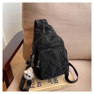 Detail of black pleated crossbody bag with triple zippers and cute bear charm