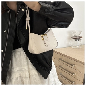 Détail du sac sous l'aisselle crème avec boucle dorée et bandoulière à nœud élégante