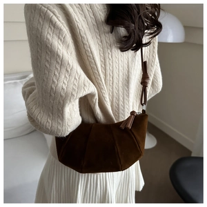 Detail of dark brown pleated suede crescent bag with textured folds and knot strap