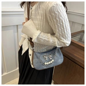 Détail d'un sac à bandoulière en jean avec boucle papillon argentée et chaîne de perles