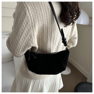 Model wearing a black matte half-moon shoulder bag with a stylish knotted strap design