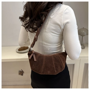 Detail view of dark brown suede crescent bag with pleated design and knot shoulder strap