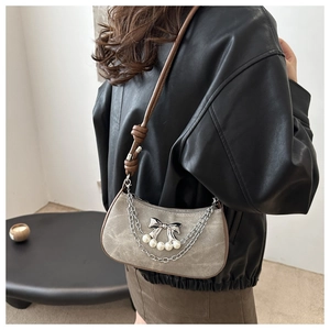 Detail of grey canvas crossbody bag with silver bow, pearls, and metallic chains