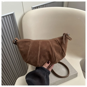 Detail showing deep brown suede texture and pleated design of the crescent shoulder bag