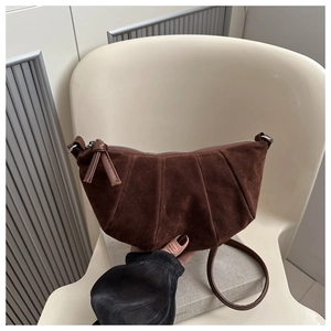 Detail of dark brown suede crescent bag featuring pleated texture and zipper pullers