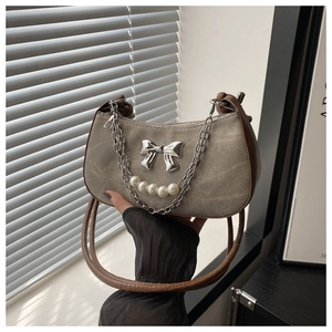 Détail du sac hobo vintage avec nœud métallique, chaîne perle et bordure en cuir