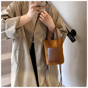Close-up of brown suede crossbody bag with smooth leather pocket and adjustable strap