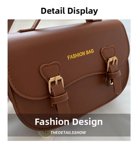 Gros plan sur la texture en cuir du sac besace marron et boucles à motif cœur
