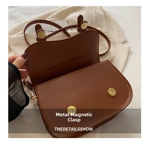 Détail d'un sac besace en cuir marron montrant deux boutons pression magnétiques dorés