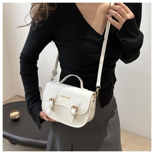 Sacoche blanche moderne avec lettrage doré, portée avec une tenue noire et grise chic
