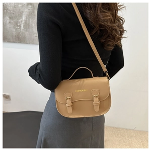 Détail du sac bandoulière en similicuir beige avec boucle coeur et lettrage fashion