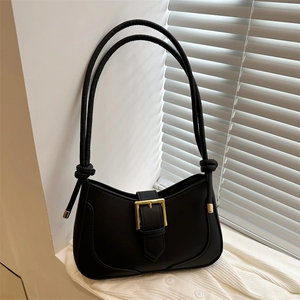 Sac sous le bras noir élégant avec boucle dorée sur fond de cardigan en maille