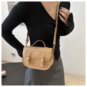 Détail du sac selle kaki avec boucle en forme de cœur et lettrage logo doré sur le cuir