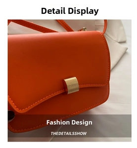 Close-up of bright orange faux leather bag with brushed gold rectangular buckle