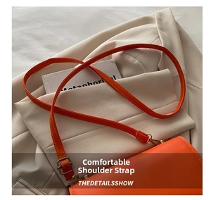Detail of adjustable orange leather shoulder strap with vintage gold buckle on a blazer