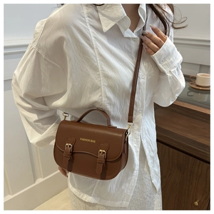 Détail du sac bandoulière en cuir marron foncé avec doubles boucles et lanière