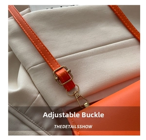 Detail of adjustable metal buckle and lobster clasp on bright orange PU leather shoulder strap