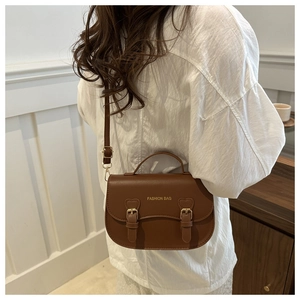 Détail du sac selle marron avec lettrage doré FASHION BAG et boucles en forme de cœur