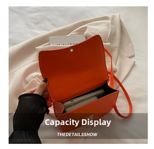 Detail view of the orange crossbody bag interior capacity with everyday items shown