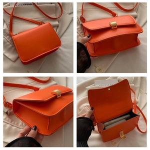 Detail view of orange faux leather crossbody bag featuring gold buckle and internal storage