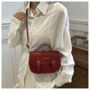 Détail du sac de selle rouge vintage avec boucles métalliques et logo doré