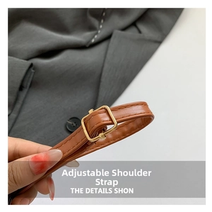 Close-up of adjustable brown leather shoulder strap with gold square buckle on a handbag