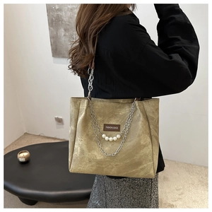 Detail of khaki suede shoulder bag featuring a stylish metal chain and pearl decoration