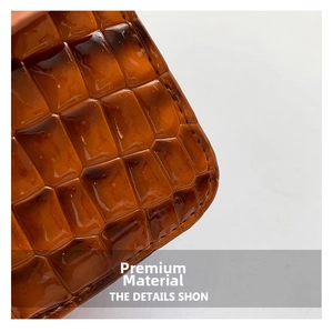 Detail of amber brown glossy faux crocodile leather with premium stitching for handbag