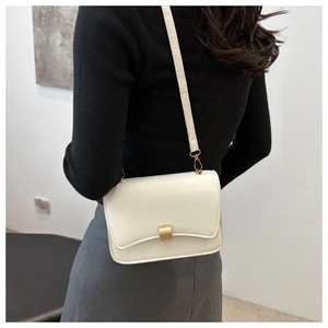 Close-up of minimalist beige crossbody bag with gold metal buckle on a shoulder strap