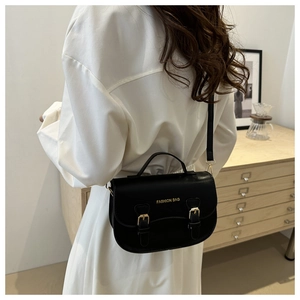 Vue arrière d'un sac besace noir rétro avec boucles dorées porté par un mannequin chic