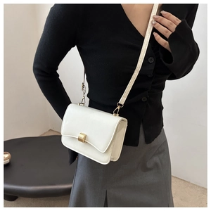 Close-up of a white leather crossbody bag featuring a golden rectangular twist lock buckle