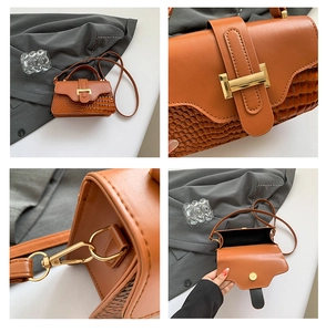 Detail of brown faux crocodile leather texture and golden hardware on crossbody bag