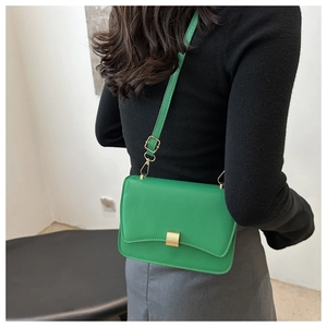 Detail of green leather baguette bag featuring wave-edge flap and gold metal buckle
