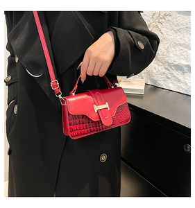Detail of red leather crossbody bag featuring crocodile texture and gold H-buckle lock