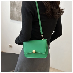 Detail of bright green leather flap bag with gold rectangular buckle shown on shoulder