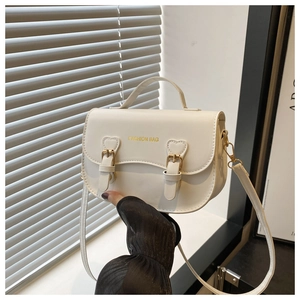 Détails du sac selle crème avec ferrures dorées et sangles décorées de coutures en cœur
