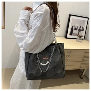 Detail of grey tote bag featuring metal chain with pearl accents and leather label
