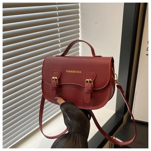 Détail du sac de selle rouge avec patchs cœurs, boucles dorées et poignée