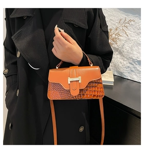 Detail of a brown shoulder bag featuring gold H-buckle and crocodile pattern leather