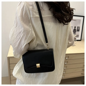 Minimalist black baguette bag shown with elegant outfit and golden metallic buckle