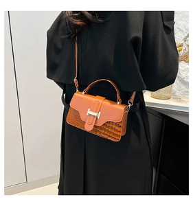 Detail of orange patchwork leather crossbody bag with iconic H buckle on black coat